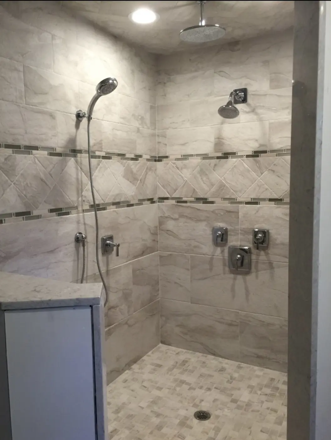 Finished tiled shower with multiple shower fixtures and controls